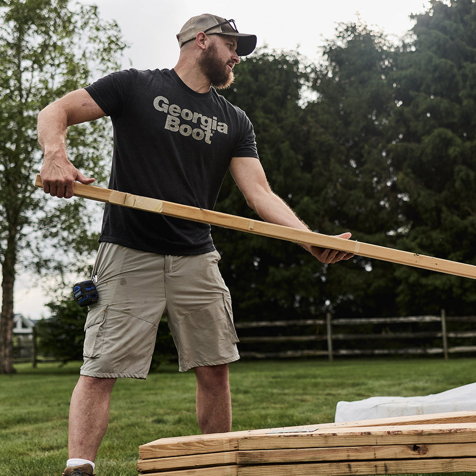 Guy wearing a Georgia Boot shirt handling lumber.