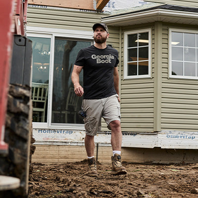 Man standing in front of a house with construction materials on the ground