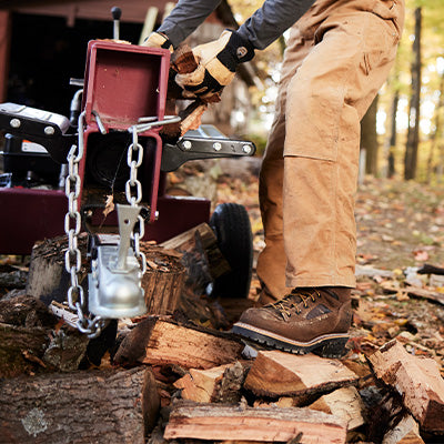 Person using a chainsaw to cut wood in a forest setting