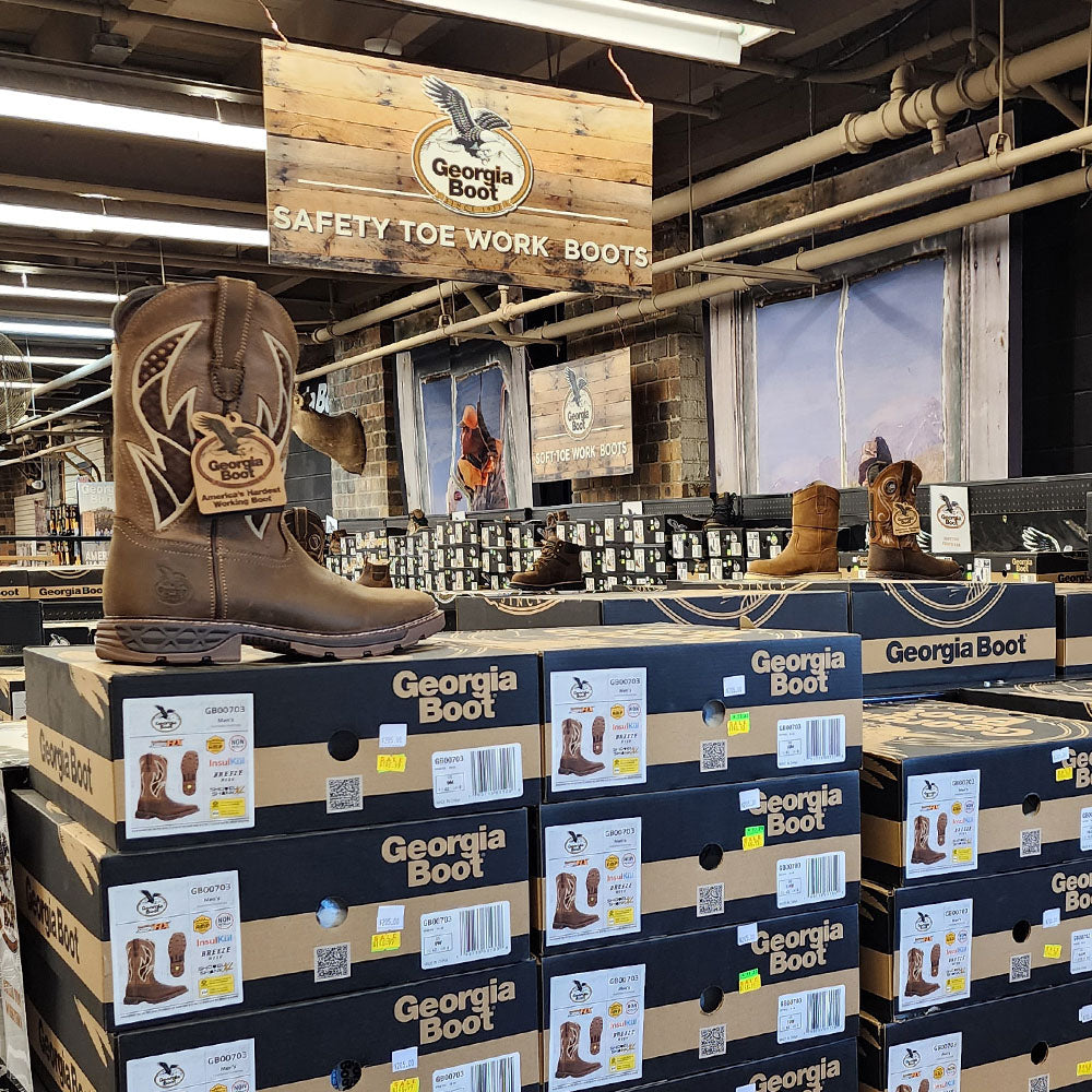 Stack of Georgia Boot boxes with a boot on top in a store setting.