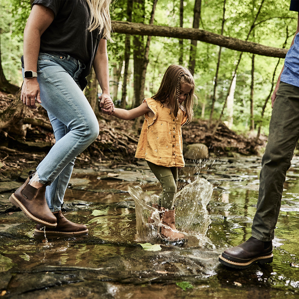 Family with a child playing in a forest stream
