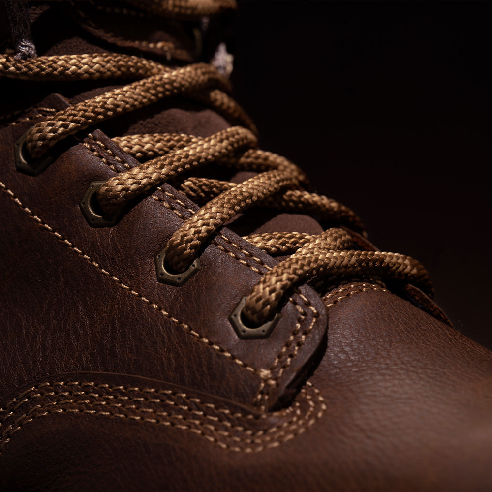 Close-up of a brown leather boot with braided laces on a dark background