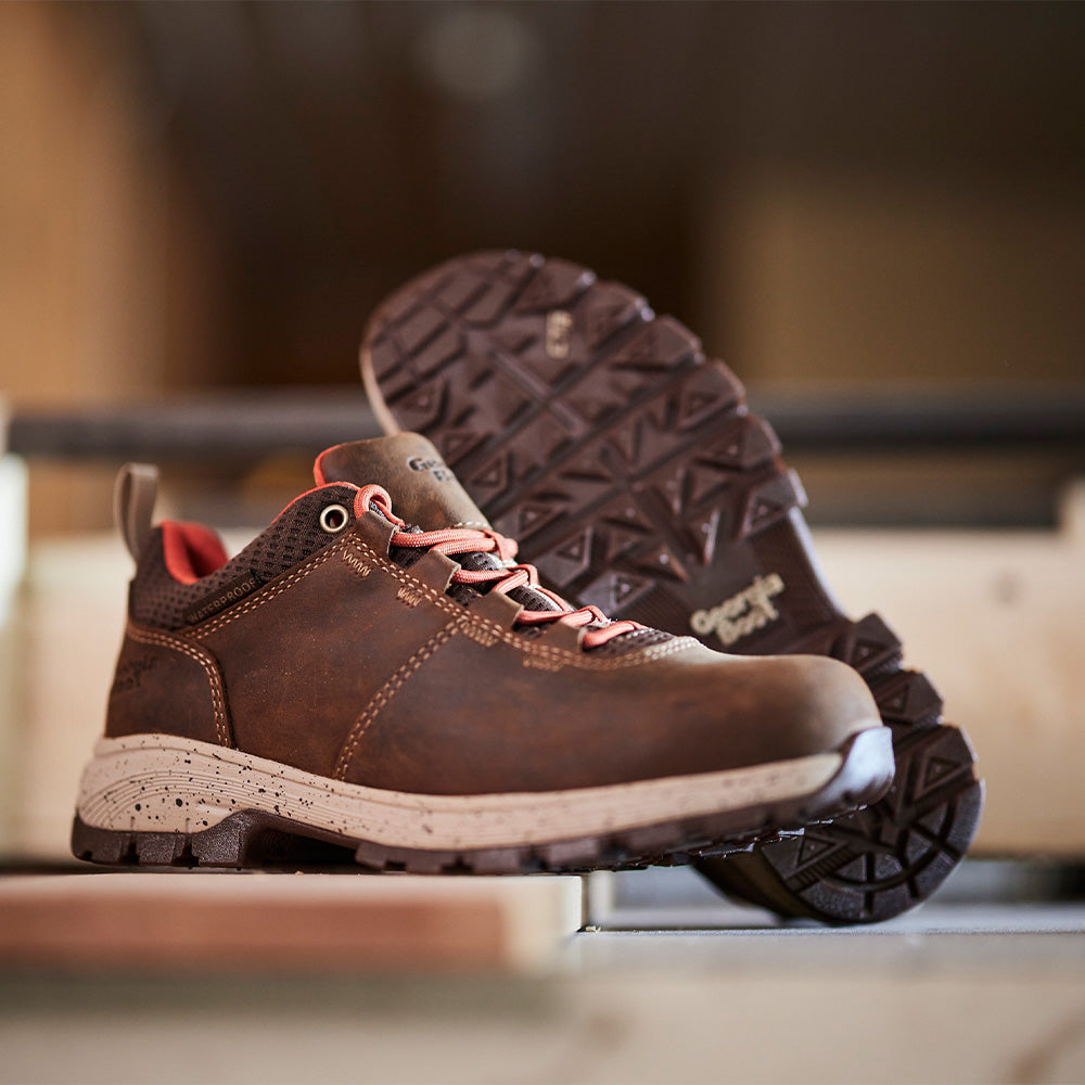 Brown hiking boots with red laces on a wooden surface