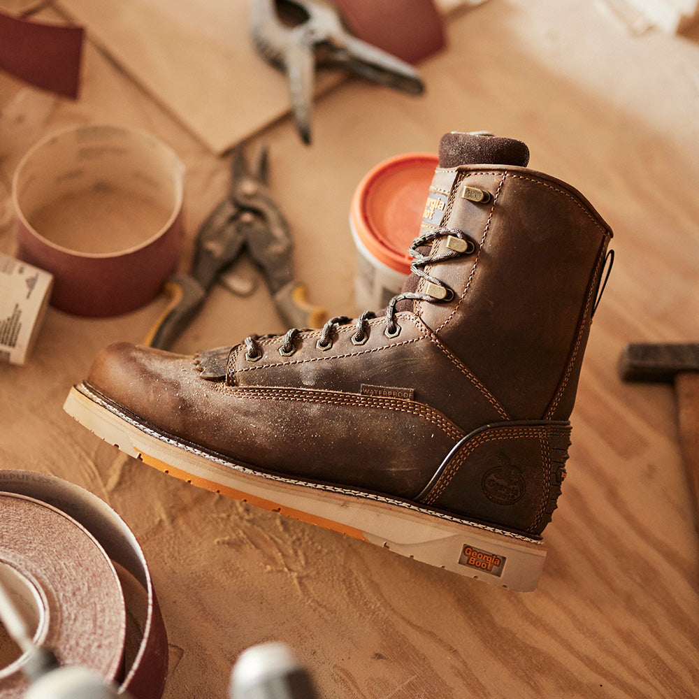 Brown work boot on a wooden surface with tools in the background