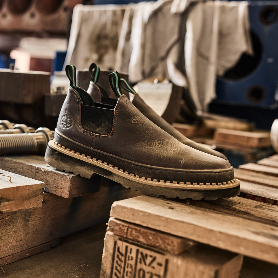 Brown leather shoes on a wooden surface with a workshop background