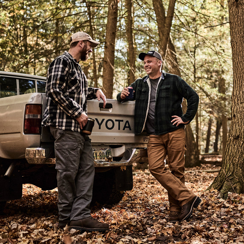 Two men standing next to a Toyota truck in a forest setting