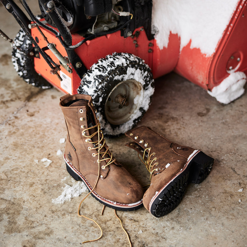 Brown work boots on a concrete floor with a snowblower in the background