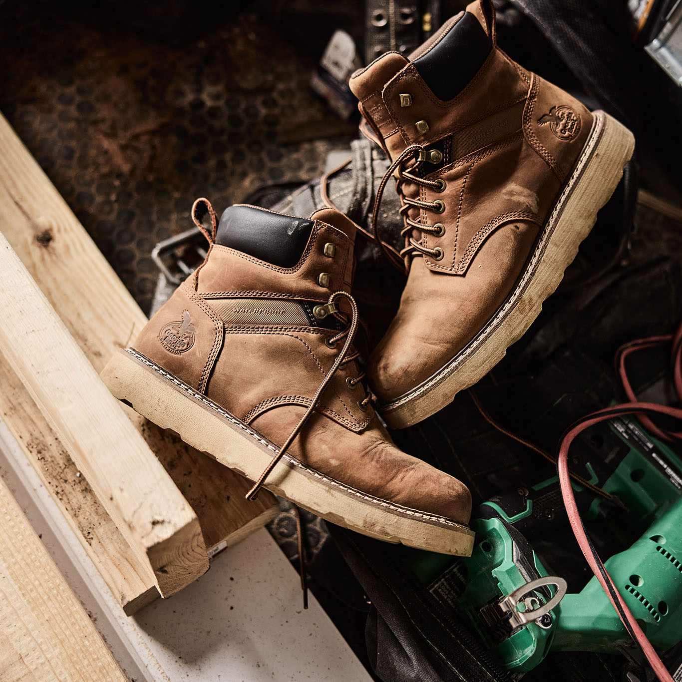 Pair of brown work boots on a construction site with tools and materials.