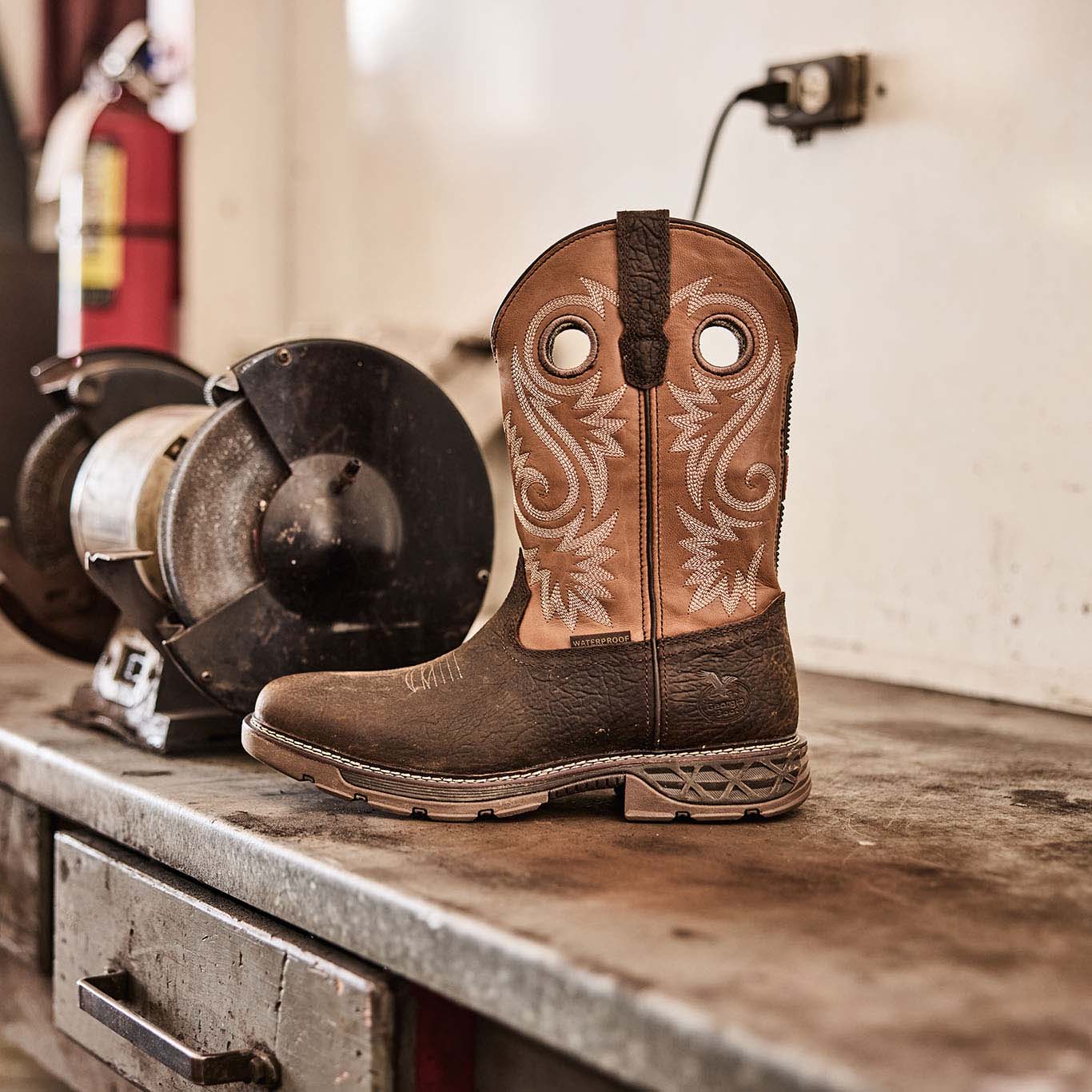 Brown cowboy boot with intricate design on a wooden surface in a workshop setting.