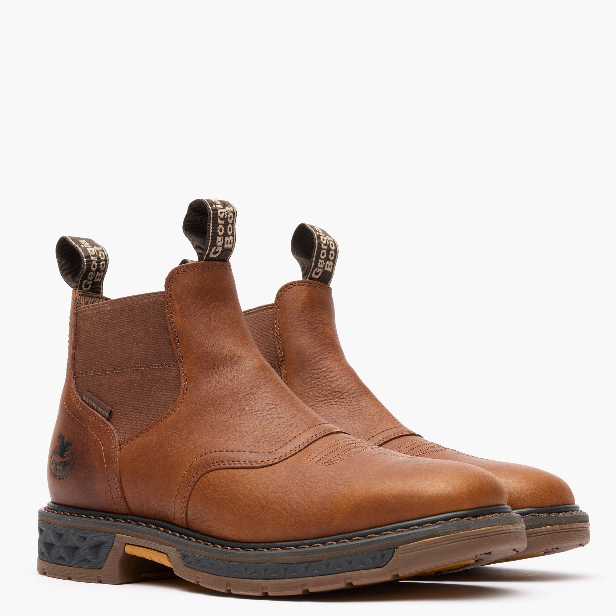 Pair of brown leather boots with black soles on a white background
